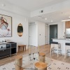 wide shot of living room with trendy rug and mosswood cabinetry kitchen