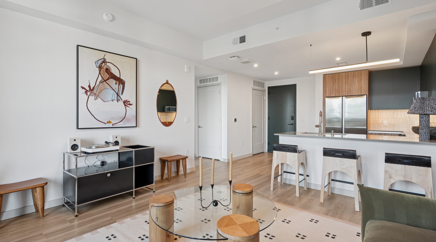 wide shot of living room with trendy rug and mosswood cabinetry kitchen
